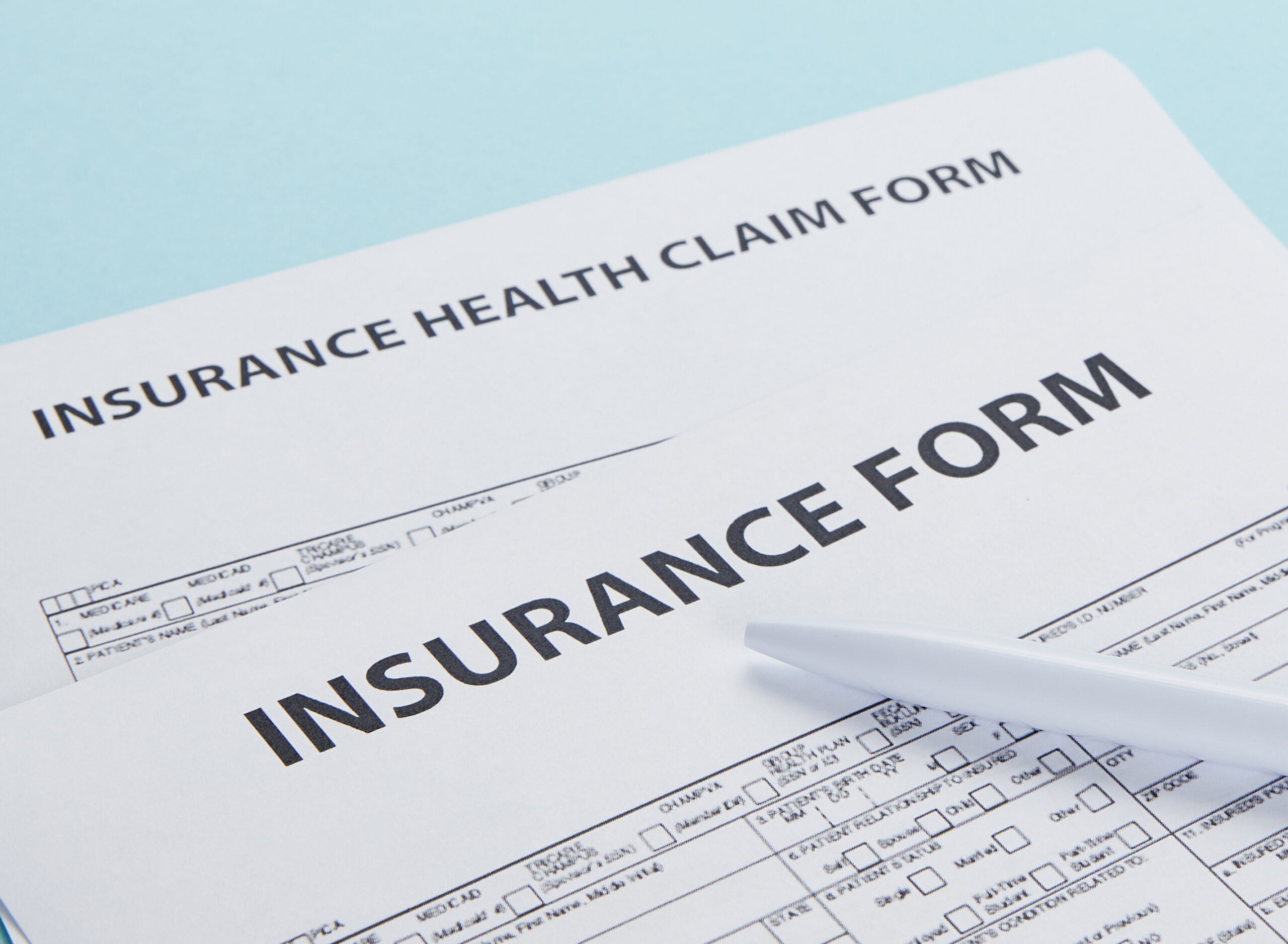 close-up view of insurance form, insurance health claim form and pen isolated on blue