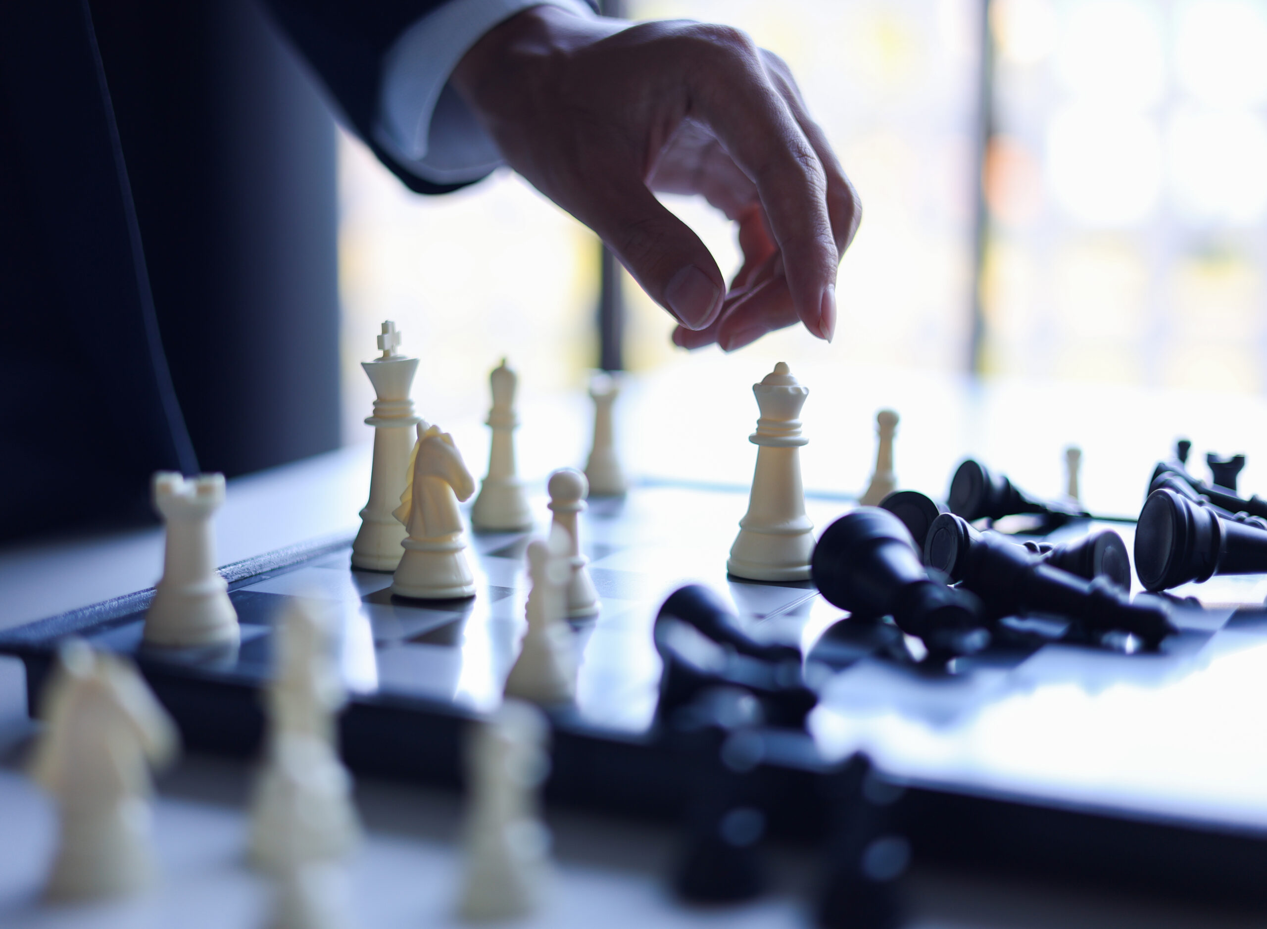 Businessman wearing suit, playing chess, game of strategy, leadership and management concept.